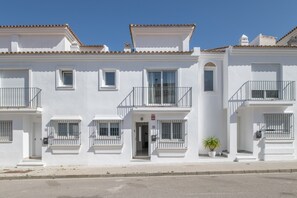 Un bâtiment blanc doté de balcons, d’une entrée centrale et d’une plante en pot.