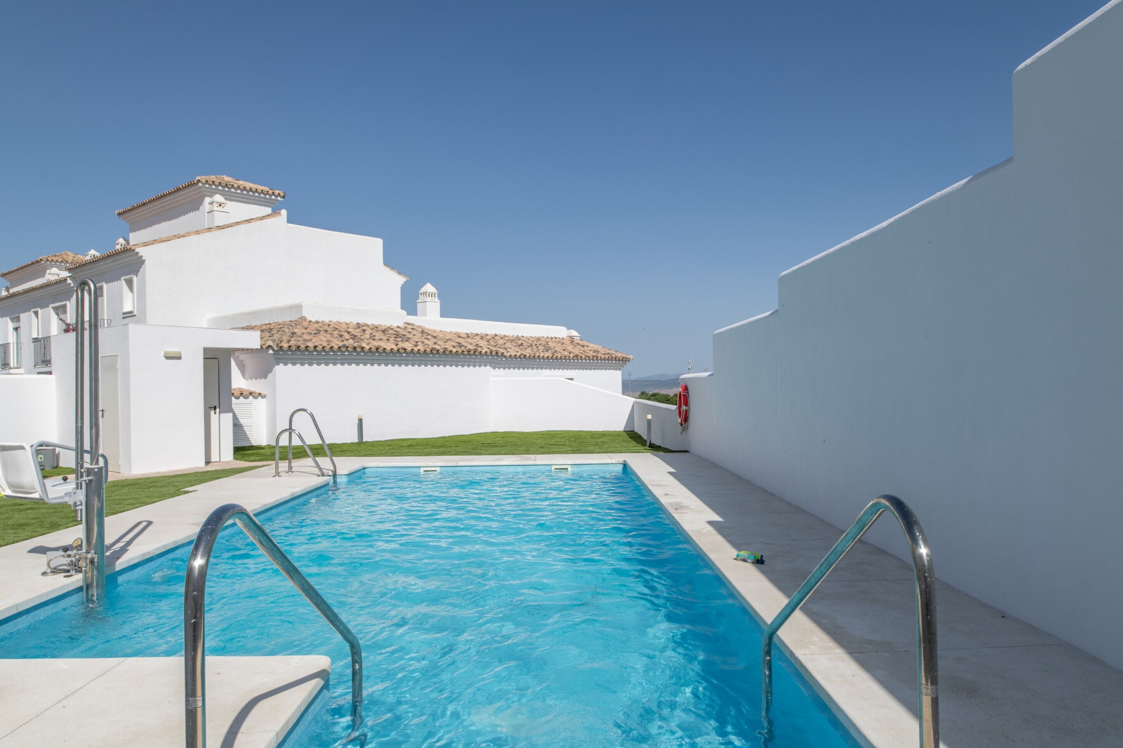 Une piscine avec un bâtiment blanc en arrière-plan.