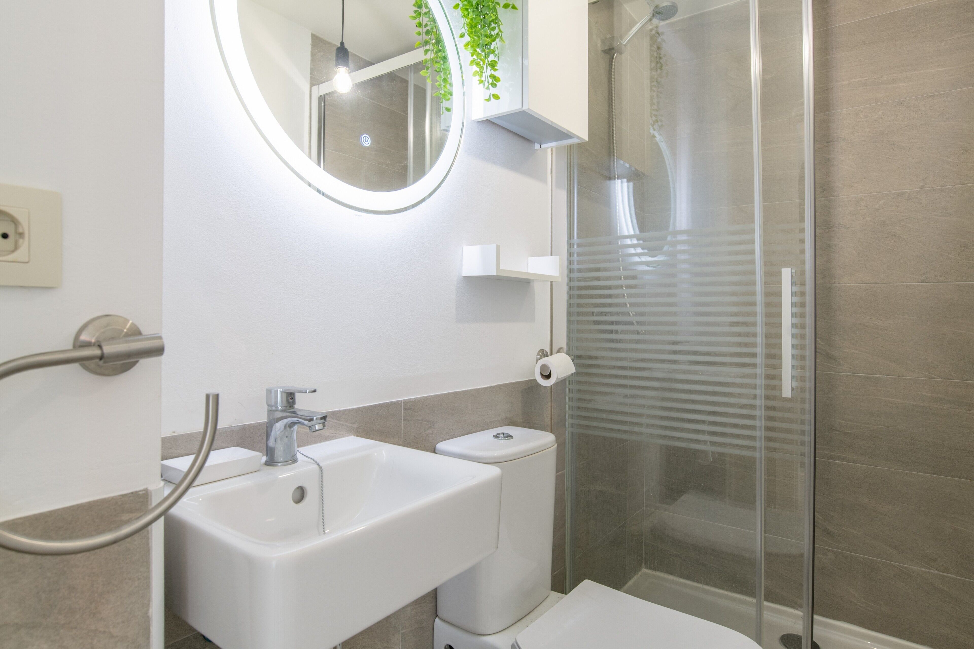 A modern bathroom with a sink, toilet, and glass shower enclosure.