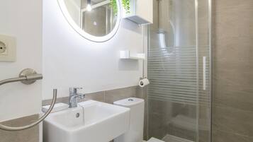 A modern bathroom with a sink, toilet, and glass shower enclosure.