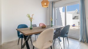 Een eetruimte met een houten tafel, blauwe en beige stoelen en een hangende lamp.