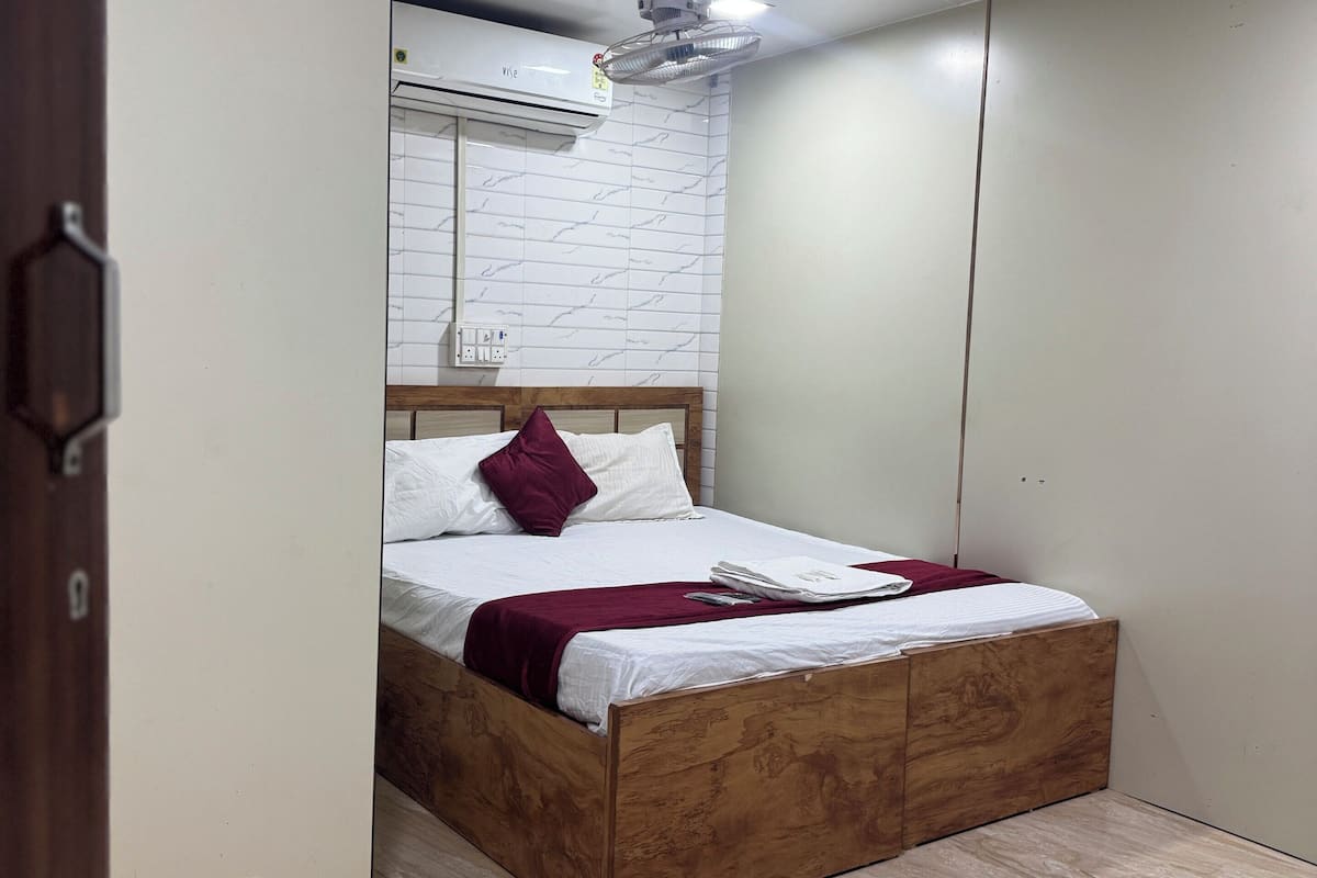 A bedroom with a wooden bed, a white air conditioning unit, and a marble floor.