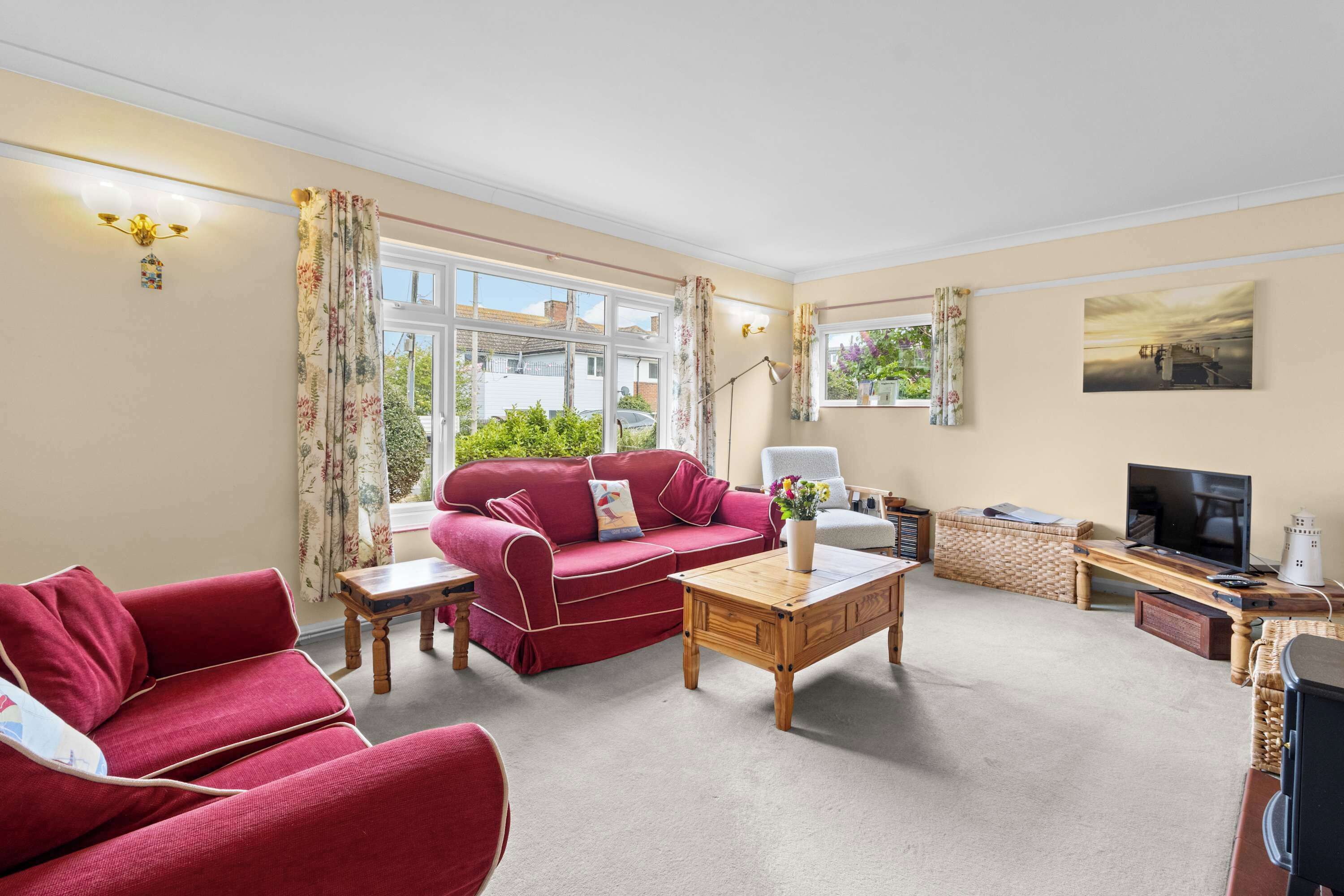 A living room with a red sofa, a wooden coffee table, a TV, and a window with curtains.