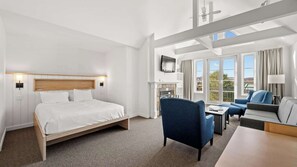 Ein Hotelzimmer mit Bett, Schreibtisch, Stuhl, Fernseher und einem Fenster mit Vorhängen.