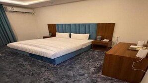 A hotel room with a bed, bedside tables, a desk, and an air conditioning unit. - Quiet Rooms 13 (Riyadh)