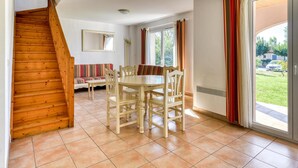 A dining area with a wooden table and chairs, a staircase, and a large window with curtains. - 8-guest House Near Mountain Trails (Homps)