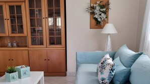 A living room with a light blue sofa, a white coffee table, and a wooden cabinet with glass doors. - Apartment '1' with Mountain View, Wi-Fi and Air Conditioning (Fanari)