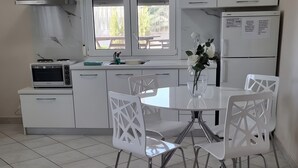 A modern kitchen with white cabinets, a gas stove, a microwave, and a refrigerator. - Apartment '1' with Mountain View, Wi-Fi and Air Conditioning (Fanari)