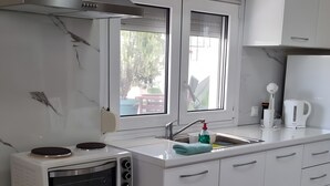 A modern kitchen with white cabinets, a built-in microwave, a stove, a window, and a sink. - Apartment '1' with Mountain View, Wi-Fi and Air Conditioning (Fanari)
