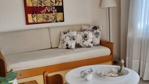 Ein Wohnzimmer mit einer Couch, einem runden weißen Tisch und einer Stehlampe.