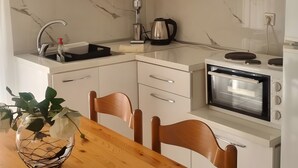 Eine moderne Küche mit weißen Schränken, einem Edelstahl-Wasserkocher, einer Mikrowelle und einem Holzespeisetisch mit Stühlen.