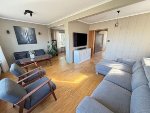 A modern living room with a sofa, chairs, a dining table, a TV, and a cabinet. - Family friendly house centrally located in Reykjavik (Reykjavík)