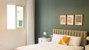 A bedroom with a bed, a nightstand, a lamp, and a window with curtains. - Tremendous 3-bedroom apartment with AC & Fast Wi-Fi in New Cairo City (New Cairo City)