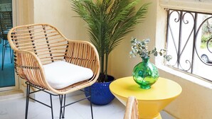 A balcony with wicker chairs, a potted plant, and a small table. - Tremendous 3-bedroom apartment with AC & Fast Wi-Fi in New Cairo City (New Cairo City)