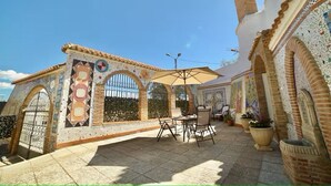 Een binnenplaats met betegelde muren, een betegelde vloer, buitenmeubels en een pergola.