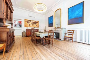 A dining room with a wooden table, chairs, a chandelier, a fireplace, and artwork on the walls. - Luxurious 130sqm apt gambetta square with AC (Carcassonne)