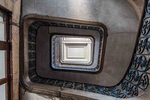 Een spiraaltrap met decoratieve metalen leuningen en een witte deur in het midden.