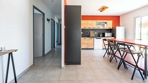 Uma cozinha moderna com área de jantar, apresentando uma ilha central, armários de madeira e uma geladeira.