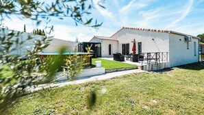Uma casa moderna com piscina, um alpendre com móveis de exterior e um gramado bem cuidado.