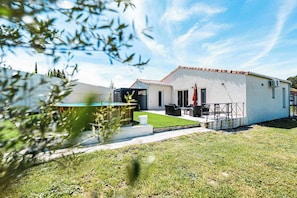 A modern house with a swimming pool, a patio with outdoor furniture, and a well-maintained lawn.