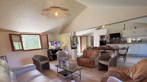 A spacious living area with leather sofas, a glass coffee table, a television, and a kitchen in the background. - Charming countryside residence, swimming pool (Allemans)