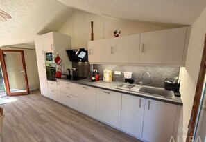 Eine moderne Küche mit weißen Schränken, einem eingebauten Backofen, einer Kaffeemaschine und einem Spülbecken.