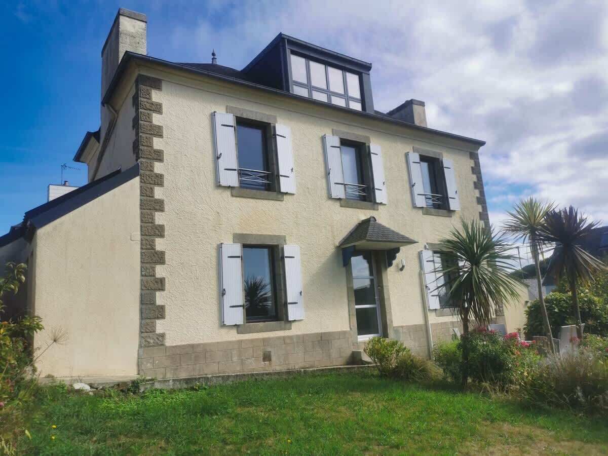 A two-story house with a balcony, a small porch, and a well-maintained lawn.