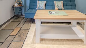 Een kamer met een blauwe bank, een houten tafel en drie ingelijste foto's aan de muur.