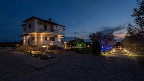 A two-story house with a balcony, stone pathway, and illuminated trees. - Stone Vista by RentalsPro - Nea Poidaia Halkidiki (Nea Poteidaia)