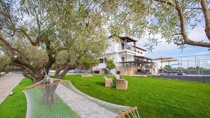 A hammock under a tree, a pool, and a building with outdoor seating. - Stone Vista by RentalsPro - Nea Poidaia Halkidiki (Nea Poteidaia)