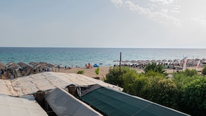 A beach with umbrellas and people, a clear sky, and a view of the sea. - Sandra Seafront Apartment by RentalsPro - Moudania Halkidiki (Nea Moudania)