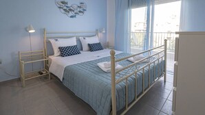 A bedroom with a bed, bedside tables, a wall decoration, and a window. - Sandra Seafront Apartment by RentalsPro - Moudania Halkidiki (Nea Moudania)