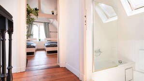 A bedroom with a wooden floor, a glass shower, and a view of a balcony. - Antwerp Old Town Apartment (Antwerp)