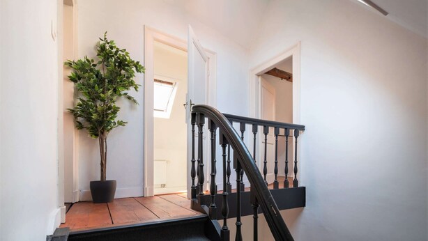 A staircase with a black balustrade leading to a room. - Antwerp Old Town Apartment (Antwerp)