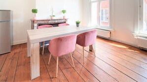 A modern kitchen with a wooden table, pink chairs, and potted plants. - Antwerp Old Town Apartment (Antwerp)