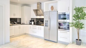 A modern kitchen with white cabinets, a stainless steel refrigerator, an oven, and a coffee maker. - Lodge Apartment in Central Antwerp (Antwerp)