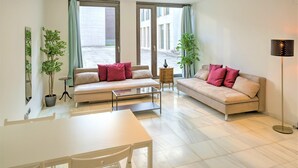A modern living room with a sofa, a dining table, and two potted plants. - Lodge Apartment in Central Antwerp (Antwerp)