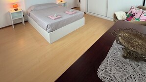 Una camera da letto con un letto, lampade da comodino, un comodino, una cassettiera e un'ampia finestra.