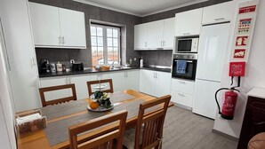 Una cucina moderna con mobili bianchi, un tavolo da pranzo con sedie, un forno a microonde e un frigorifero.