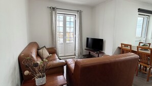 Un soggiorno con un divano in pelle marrone, un tavolino in legno, una televisione e un'area pranzo con sedie e tavolo di legno.