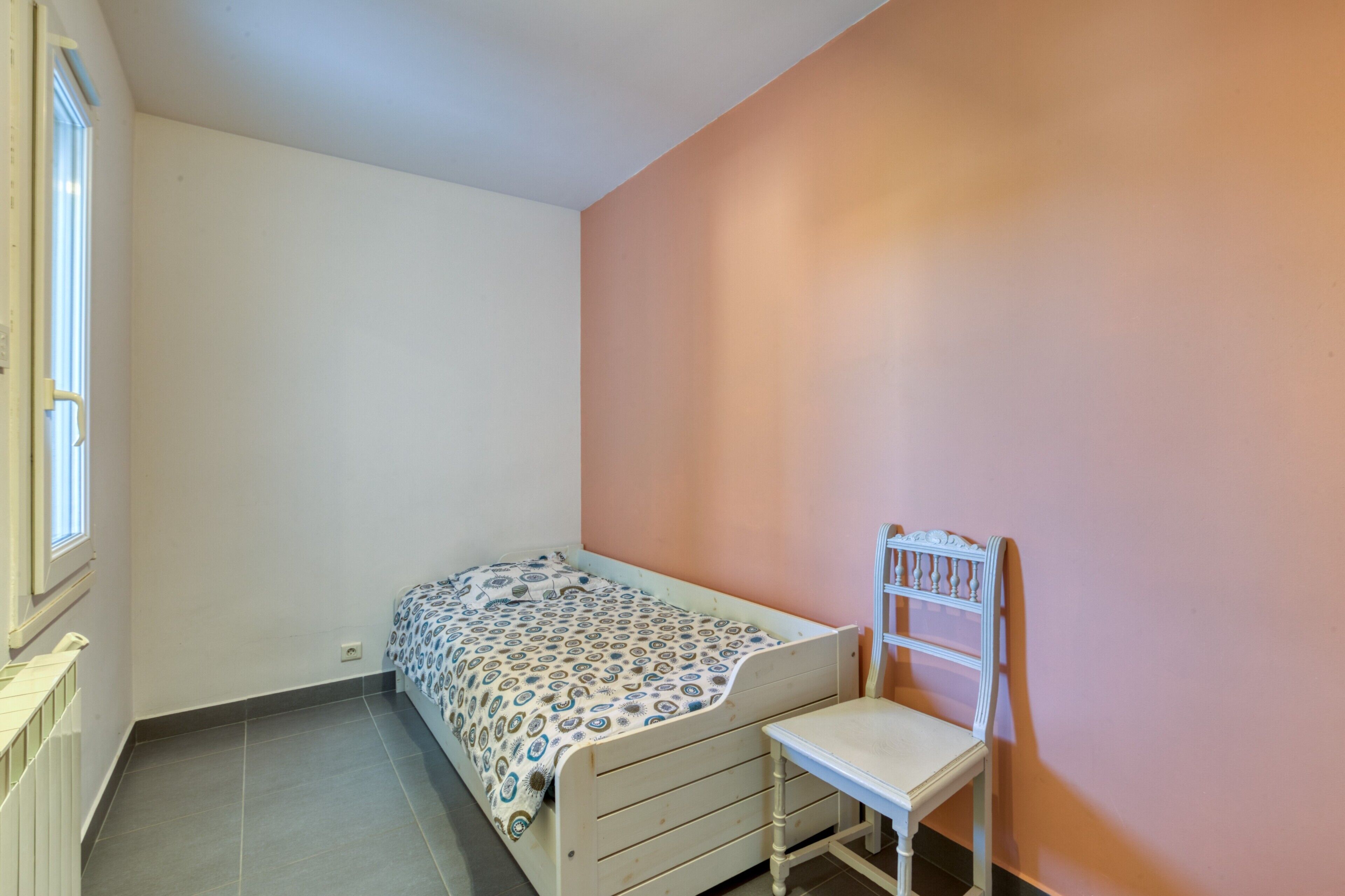Ein kleines Zimmer mit einem Einzelbett, einem Sessel und einer Heizung.