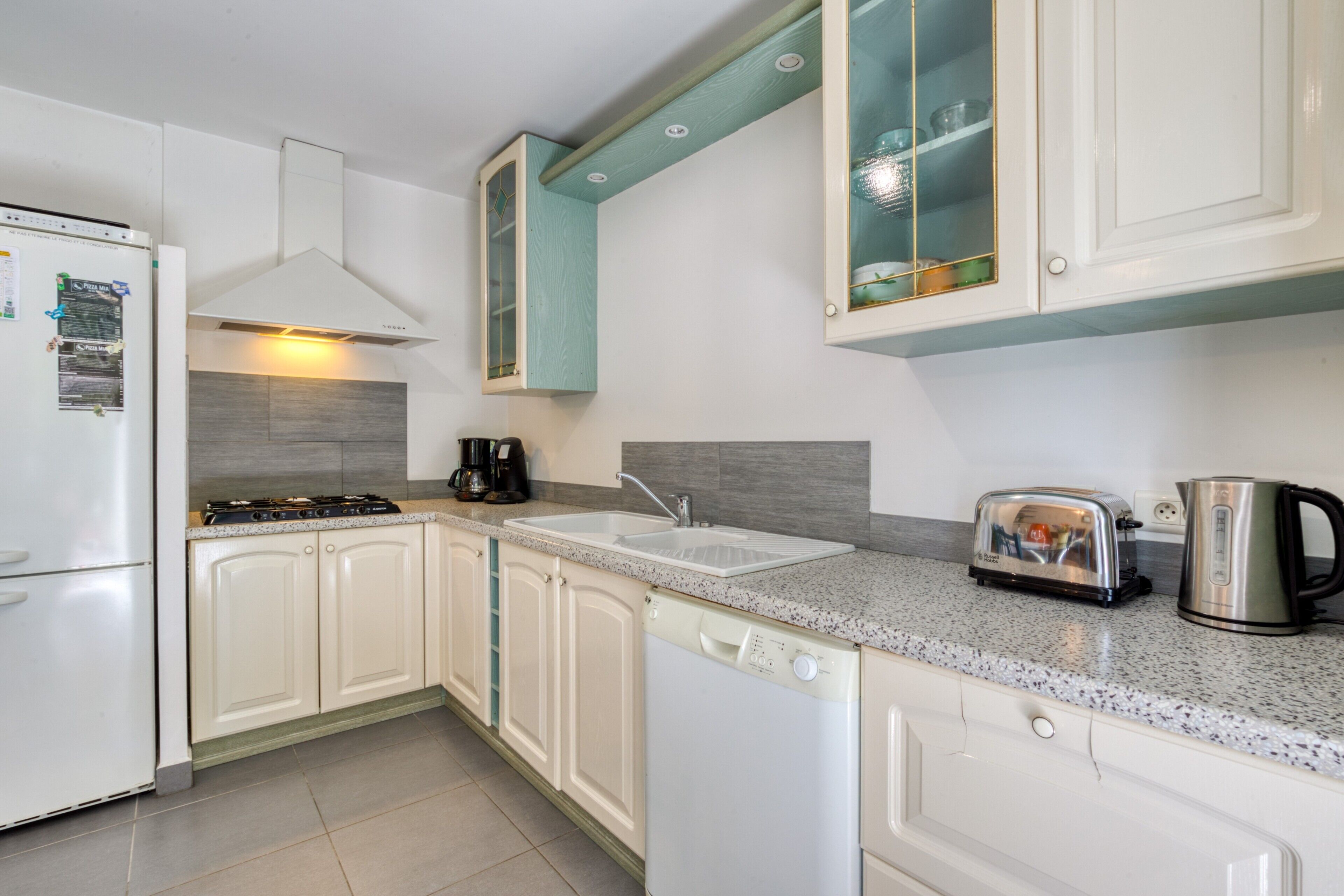 A kitchen with white cabinets, a stainless steel toaster, a coffee maker, and a dishwasher.