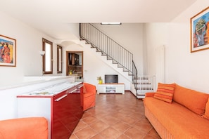 Uma sala de estar moderna com espaço para cozinha, escada e sofá.