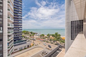 Hotel alto com várias varandas, vista para a praia e área de estacionamento.