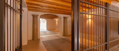 A hallway with a wooden ceiling, stone columns, and a metal gate.