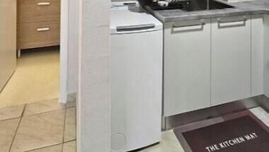Uma cozinha moderna com armários de madeira clara, forno embutido e tapete de cozinha.