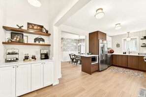 Une cuisine moderne avec des meubles blancs, des éléments décoratifs en bois et un îlot central.
