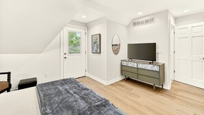A bedroom with a bed, a dresser, a television, and a door. - Sagewood Retreat! Updated spacious home on quiet st., 3 blocks from Mayo Clinic (Rochester)