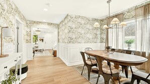 A dining area with a wooden table and chairs, a chandelier, and a view of the kitchen. - Sagewood Retreat! Updated spacious home on quiet st., 3 blocks from Mayo Clinic (Rochester)