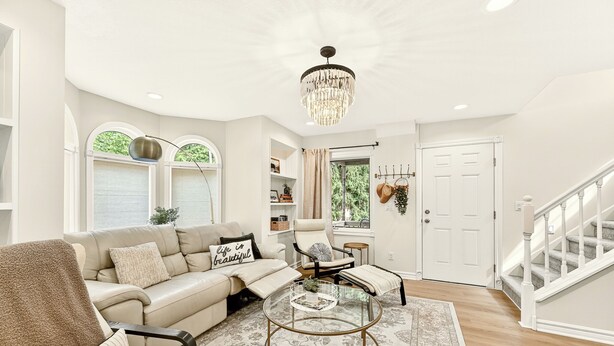 A living room with a sofa, armchairs, a coffee table, a chandelier, and a staircase. - Sagewood Retreat! Updated spacious home on quiet st., 3 blocks from Mayo Clinic (Rochester)